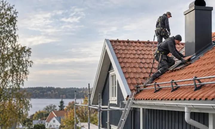 Takläggare arbetar på tegeltak till villa